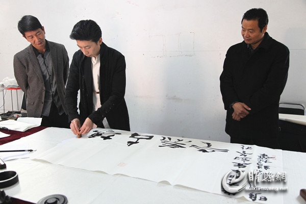 陈稳绩(中)与郭光(右)、焦凯亮在题字现场 王蔚波 摄.jpg
